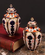 An associated pair of Royal Crown Derby ovoid vases, pierced domed covers and finials, 21cm high,