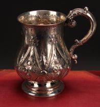 A Victorian baluster mug, chased with flowers and foliage within Gothic reserves, acanthus-capped
