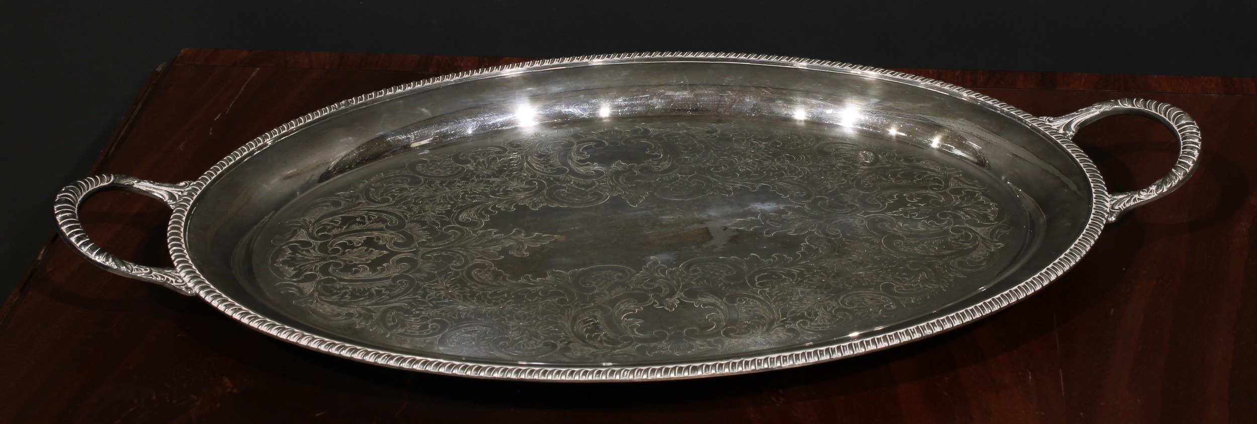 An E.P. on copper oval two-handled serving tray, gadrooned border, the field engraved with a broad