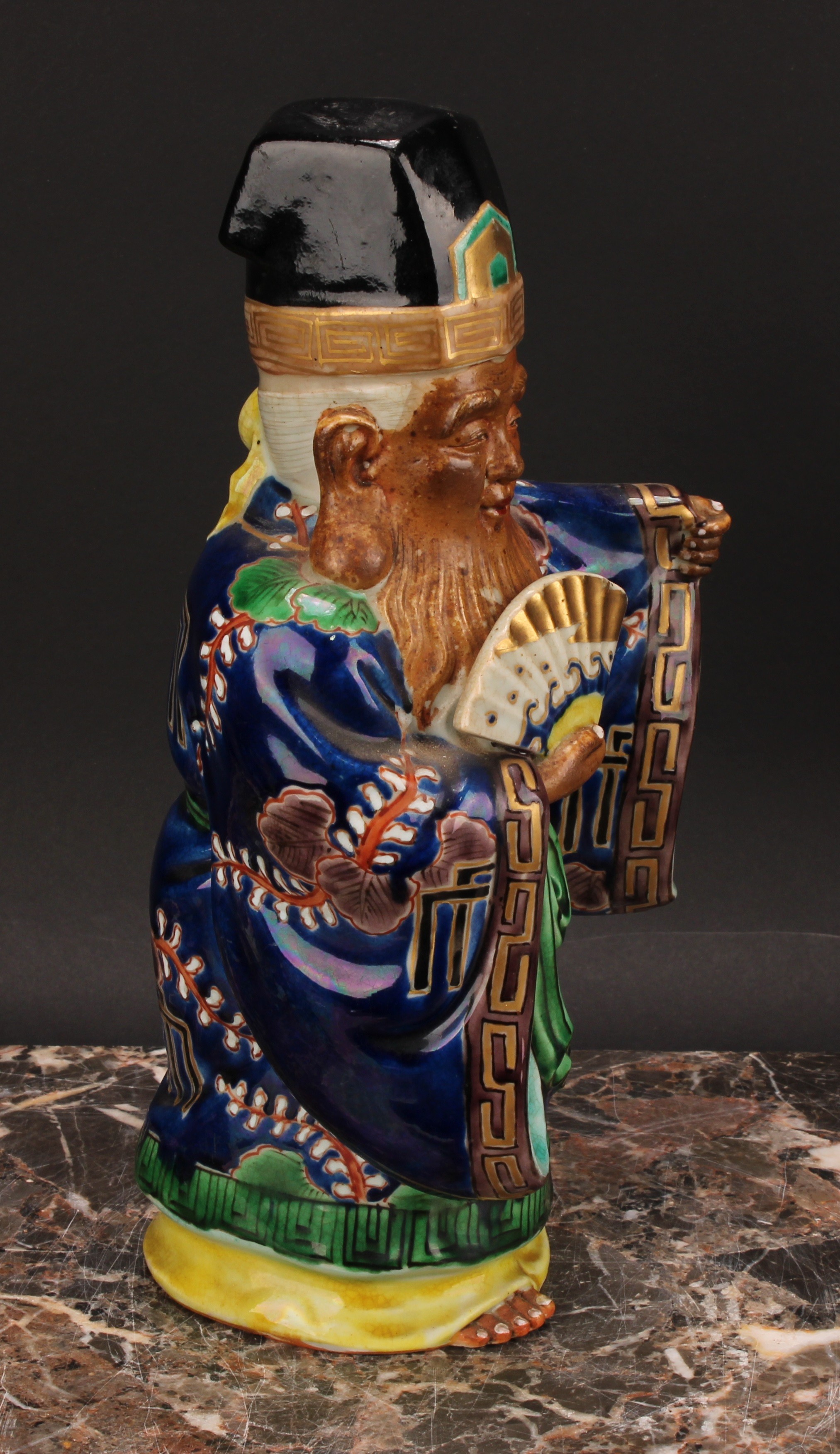 A Japanese porcelain figure, of an elder holding a fan, painted in polychrome and picked out in - Image 3 of 6