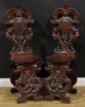 A pair of 19th century Italian walnut sgabelli or hall chairs, carved throughout in the