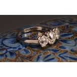 A diamond three stone ring, the central round brilliant cut stone flanked by two smaller stones,