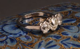 A diamond three stone ring, the central round brilliant cut stone flanked by two smaller stones,