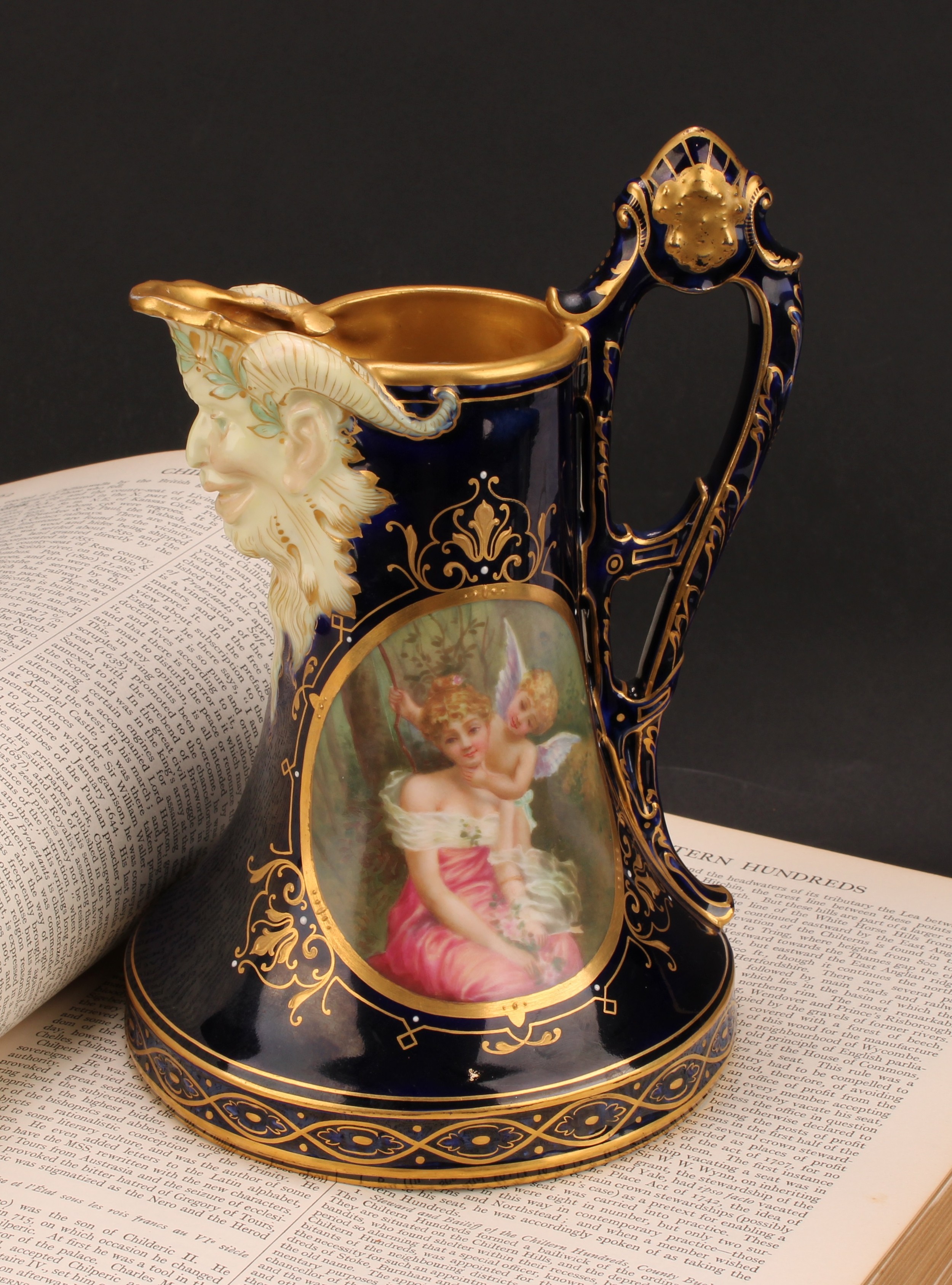 A Vienna porcelain jug, the central oval cartouche painted with Cupid and Psyche, Bacchic mask spot,