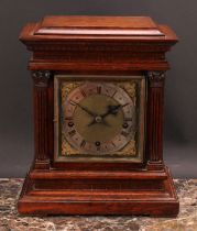 An early 20th century oak architectural bracket-form mantel clock, 15cm square brass dial with