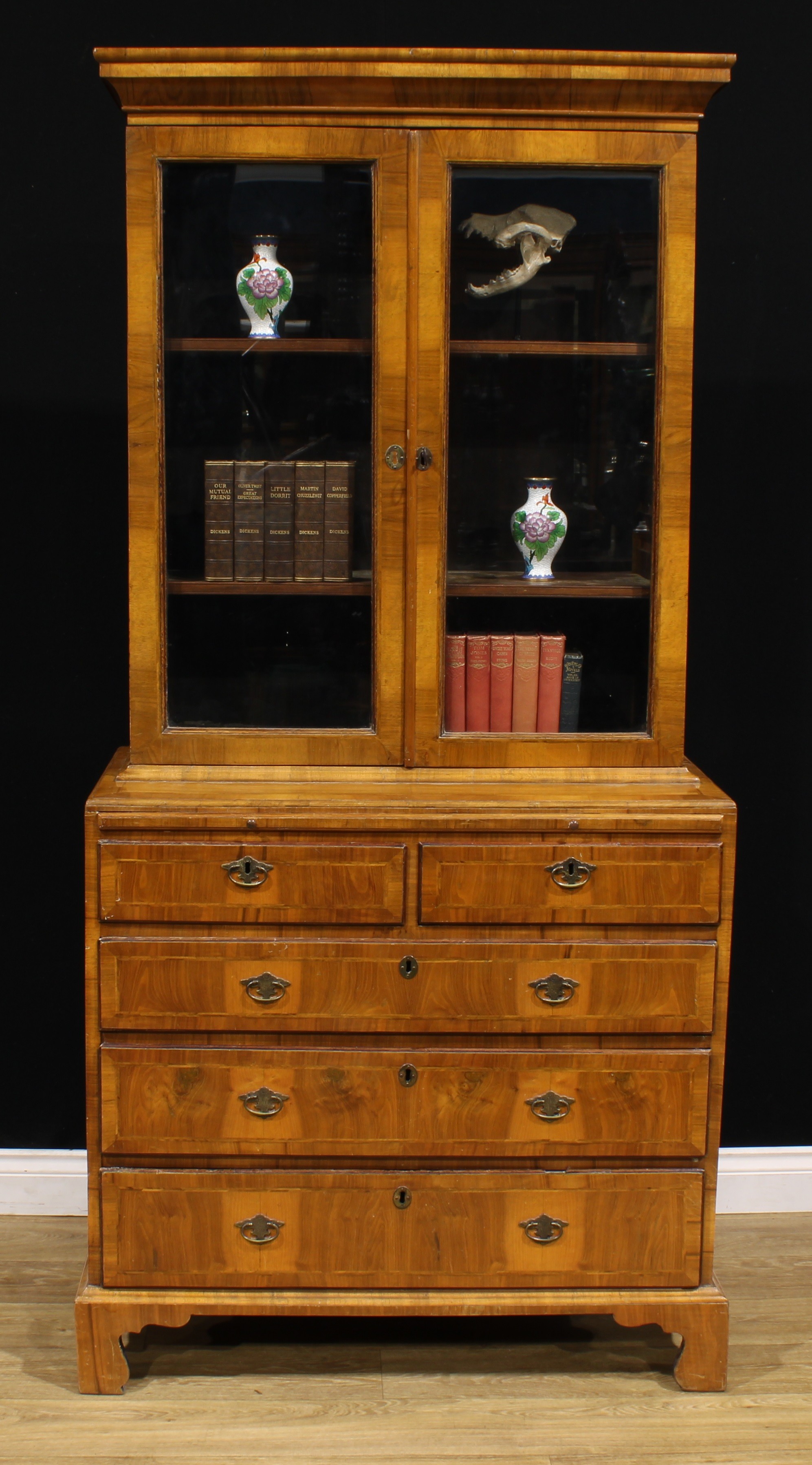 An 18th century and later walnut library bookcase, outswept cornice above a pair of glazed doors,