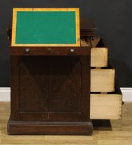 A late 19th century oak single pedestal desk, hinged top enclosing a baize surface above a long