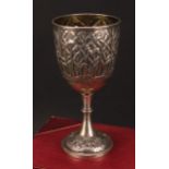 An early 20th century Indian silver pedestal wine goblet, boldly chased with continuous Musa tree
