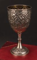 An early 20th century Indian silver pedestal wine goblet, boldly chased with continuous Musa tree