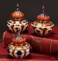 An associated pair of Royal Crown Derby 1128 Imari pattern lobed ovoid vases and covers, of