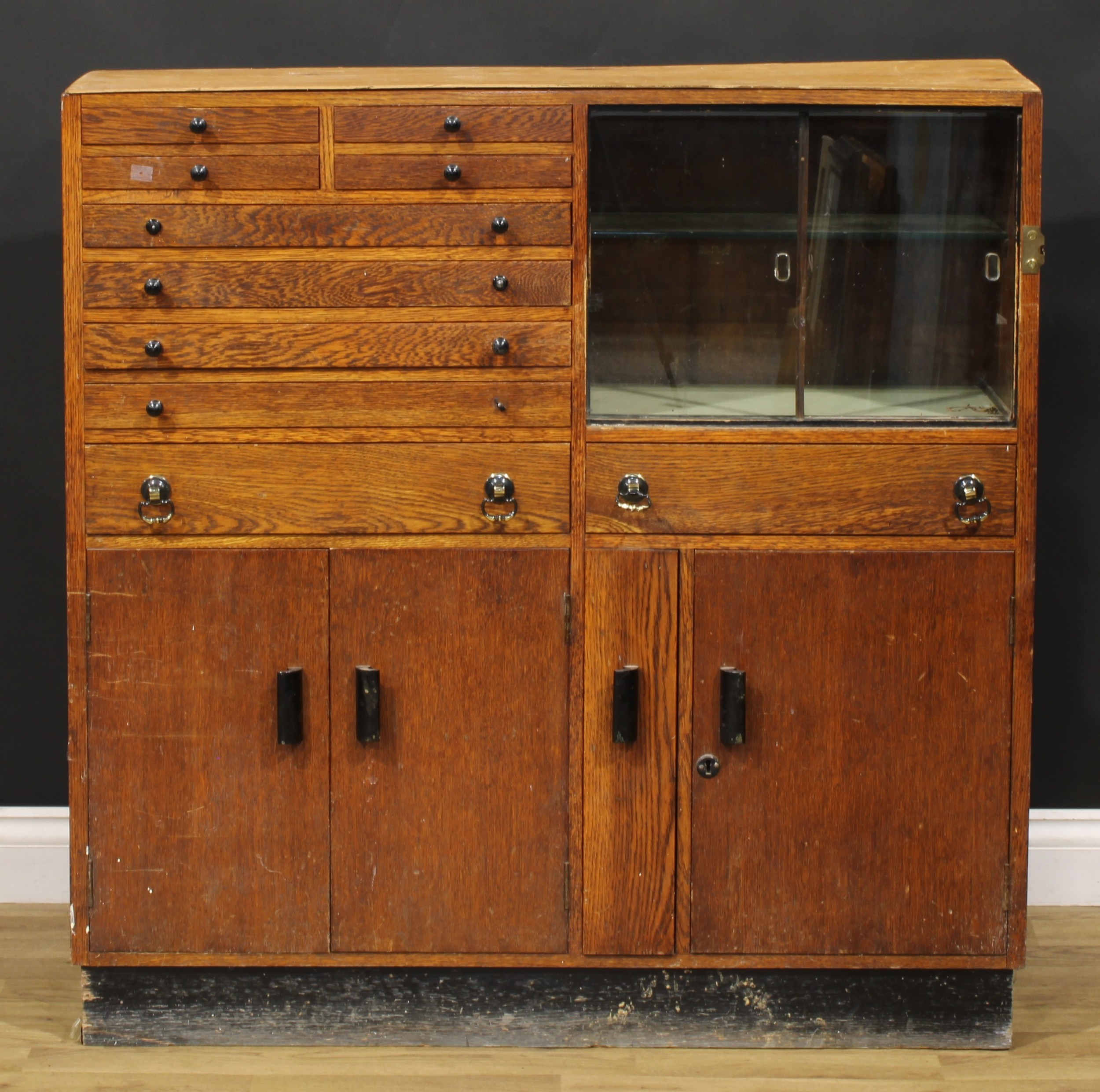 A mid-20th century oak side cabinet, now fitted for the horologist, containing various tools and
