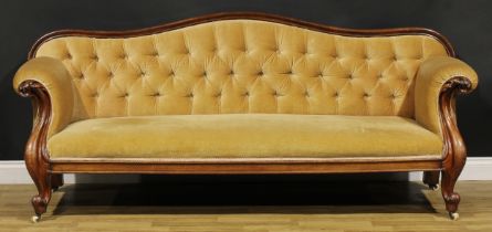 A Victorian mahogany sofa, serpentine cresting rail, stuffed-over upholstery, the arms carved with