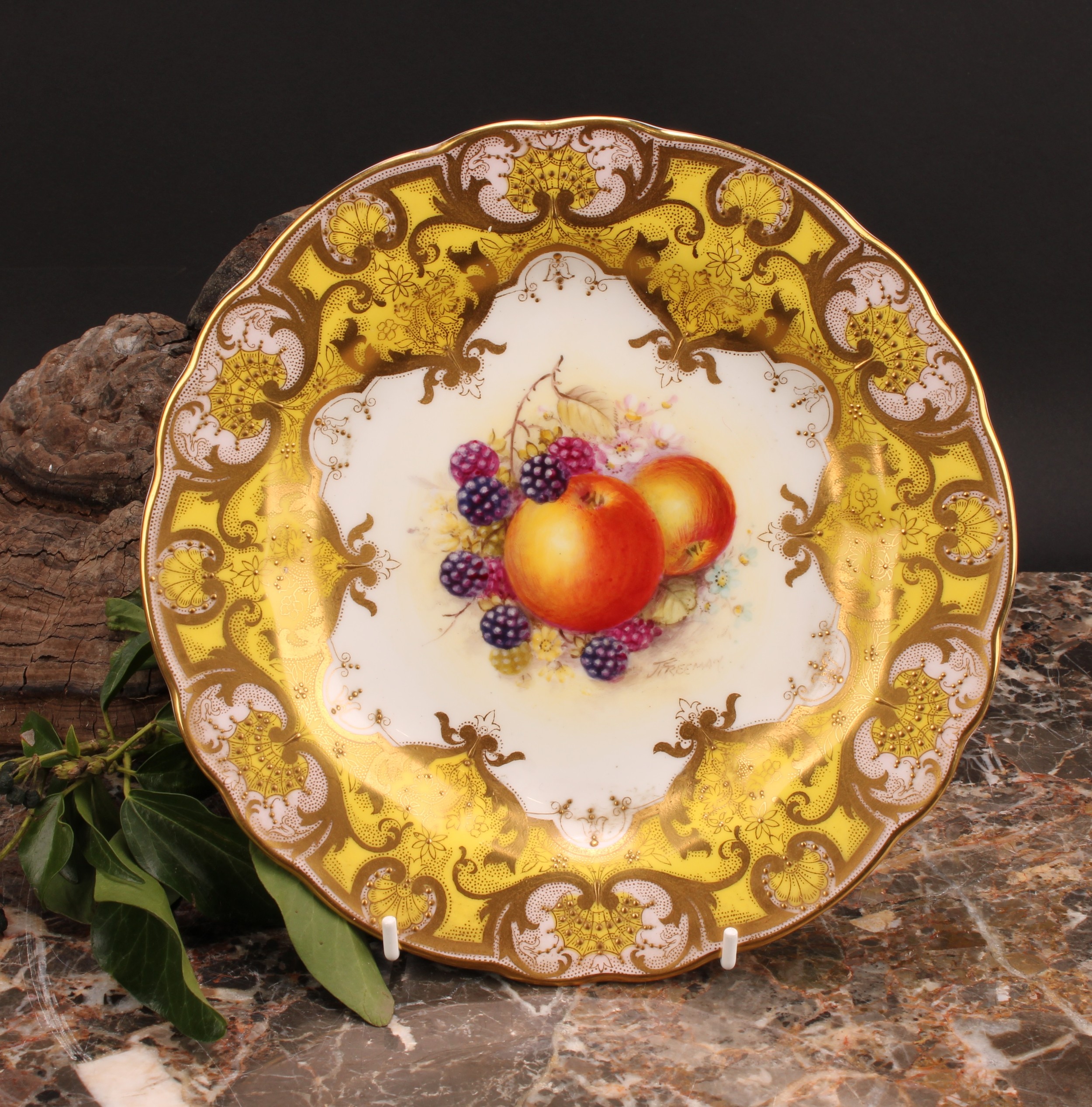 A Royal Worcester shaped circular plate, painted by J. Freeman, signed, with ripening fruit within