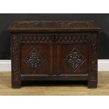 An early 18th century oak blanket chest, of small proportions, hinged three panel top carved with