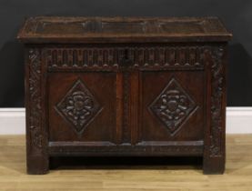 An early 18th century oak blanket chest, of small proportions, hinged three panel top carved with