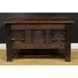 A Charles II oak three panel blanket chest, hinged top, the front profusely carved with leafy