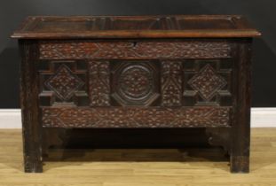 A Charles II oak three panel blanket chest, hinged top, the front profusely carved with leafy