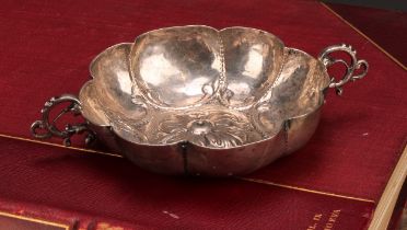 An 18th century Continental silver lobed circular wine taster, chased with a flowerhead and a band