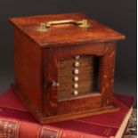 Numismatics - An Edwardian Arts and Crafts oak coin cabinet, the oversailing rectangular top with