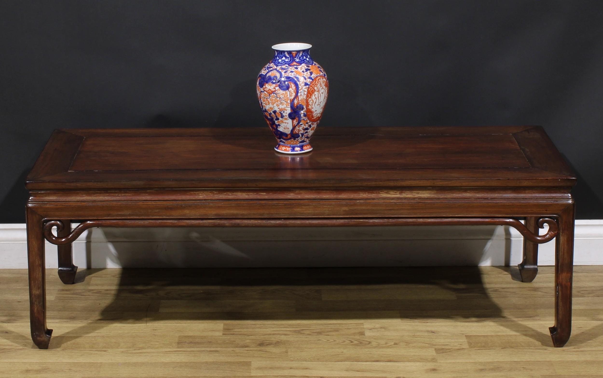 A Chinese hardwood waisted low tea table or kang table, rectangular panel top, the apron applied