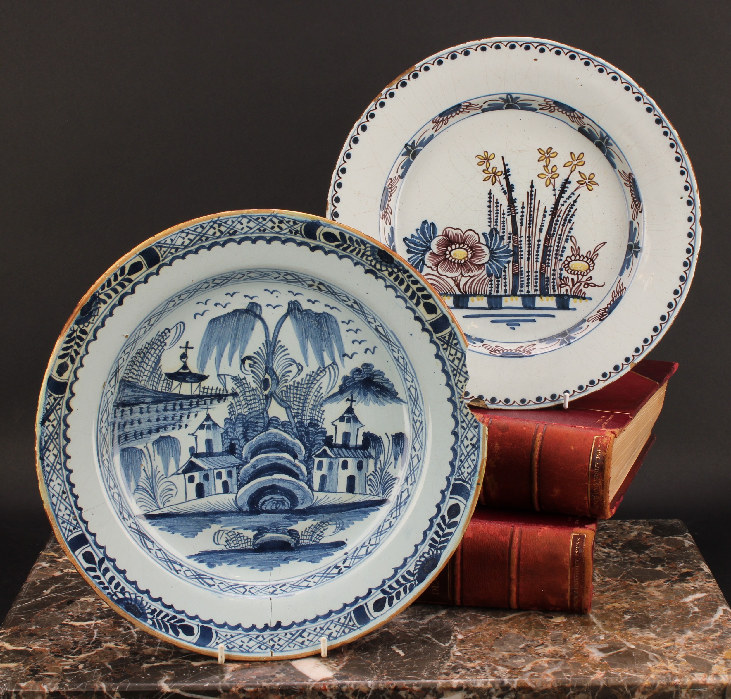 An 18th century English Delft charger, painted in underglaze blue with chinoiserie buildings,