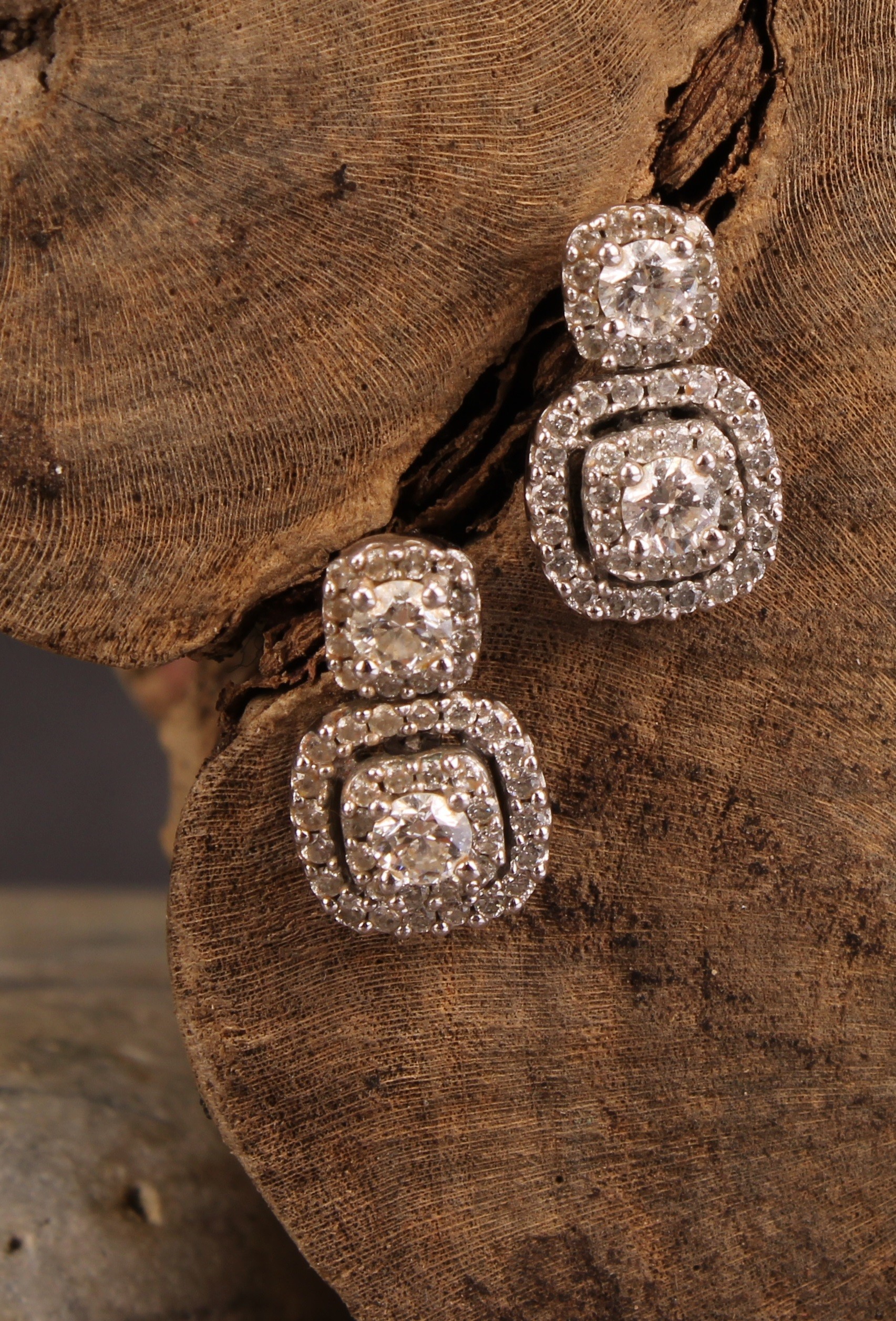 A pair diamond and 10ct white gold drop earrings, set in a halo arrangement of brilliant cut stones,