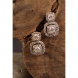 A pair diamond and 10ct white gold drop earrings, set in a halo arrangement of brilliant cut stones,