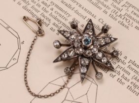 A diamond radiating starburst brooch, set with old cut stones, the central stone a faceted