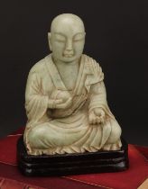 A Chinese soapstone figure, carved as a Buddhist disciple, or Luohan, holding a peach, 21cm high,