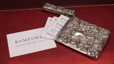 An Edwardian silver rounded rectangular visiting card case, profusely chased with flowers and