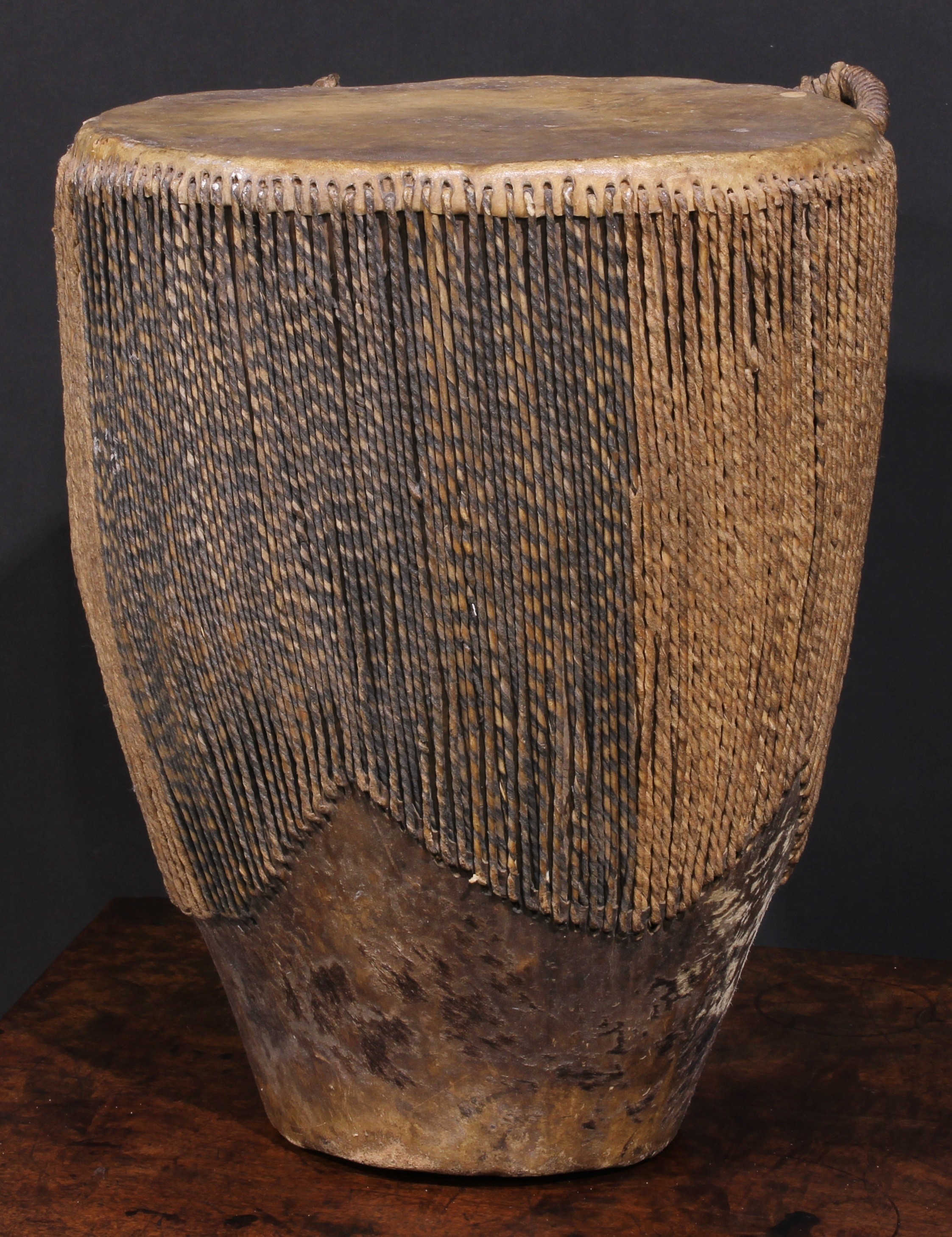 A Ugandan embuutu drum, hide bound hard wood, twin suspension loops, 39cm high, late 19th/early 20th