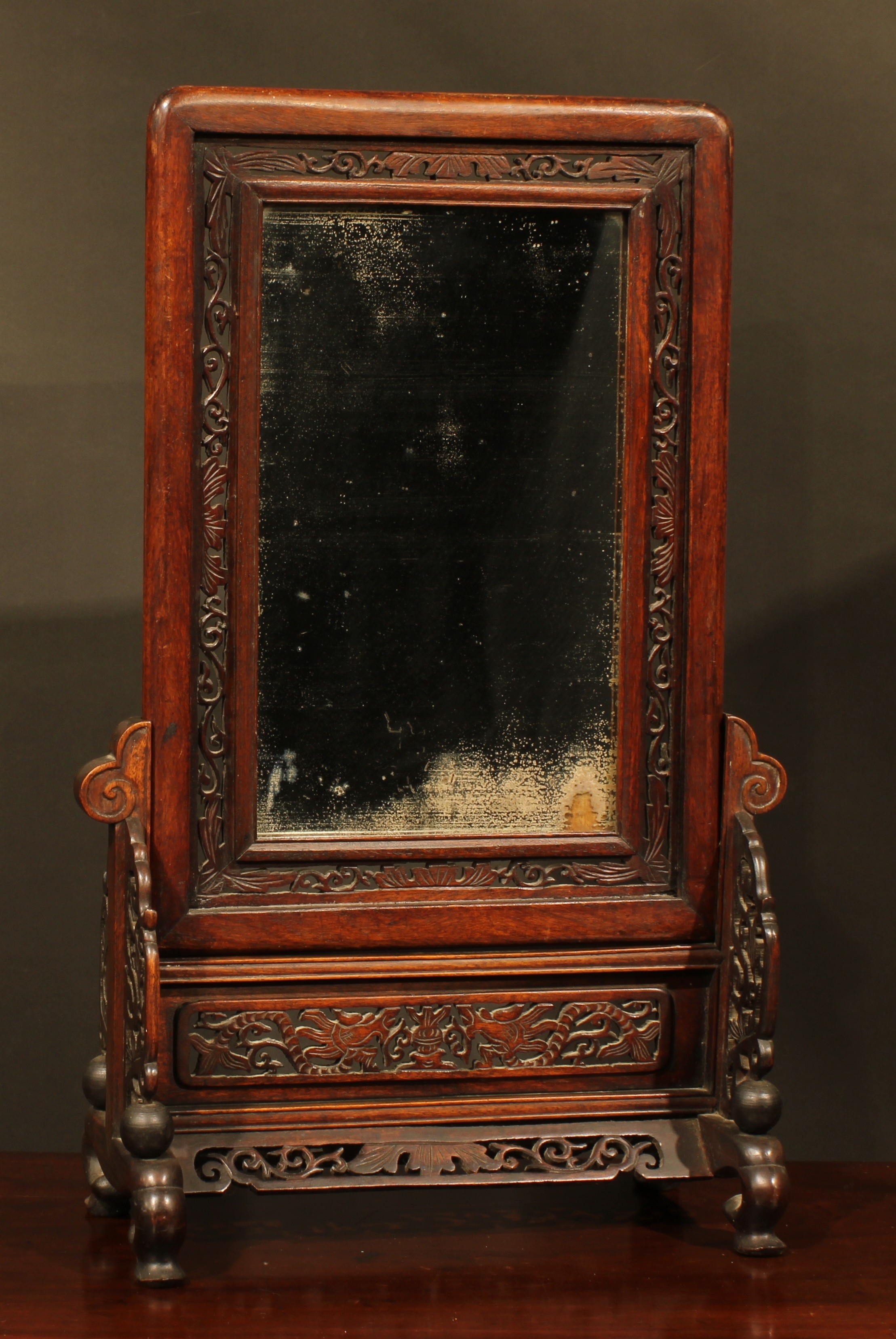 A Chinese hardwood table screen, rounded rectangular banner with mirror plate, pierced and carved