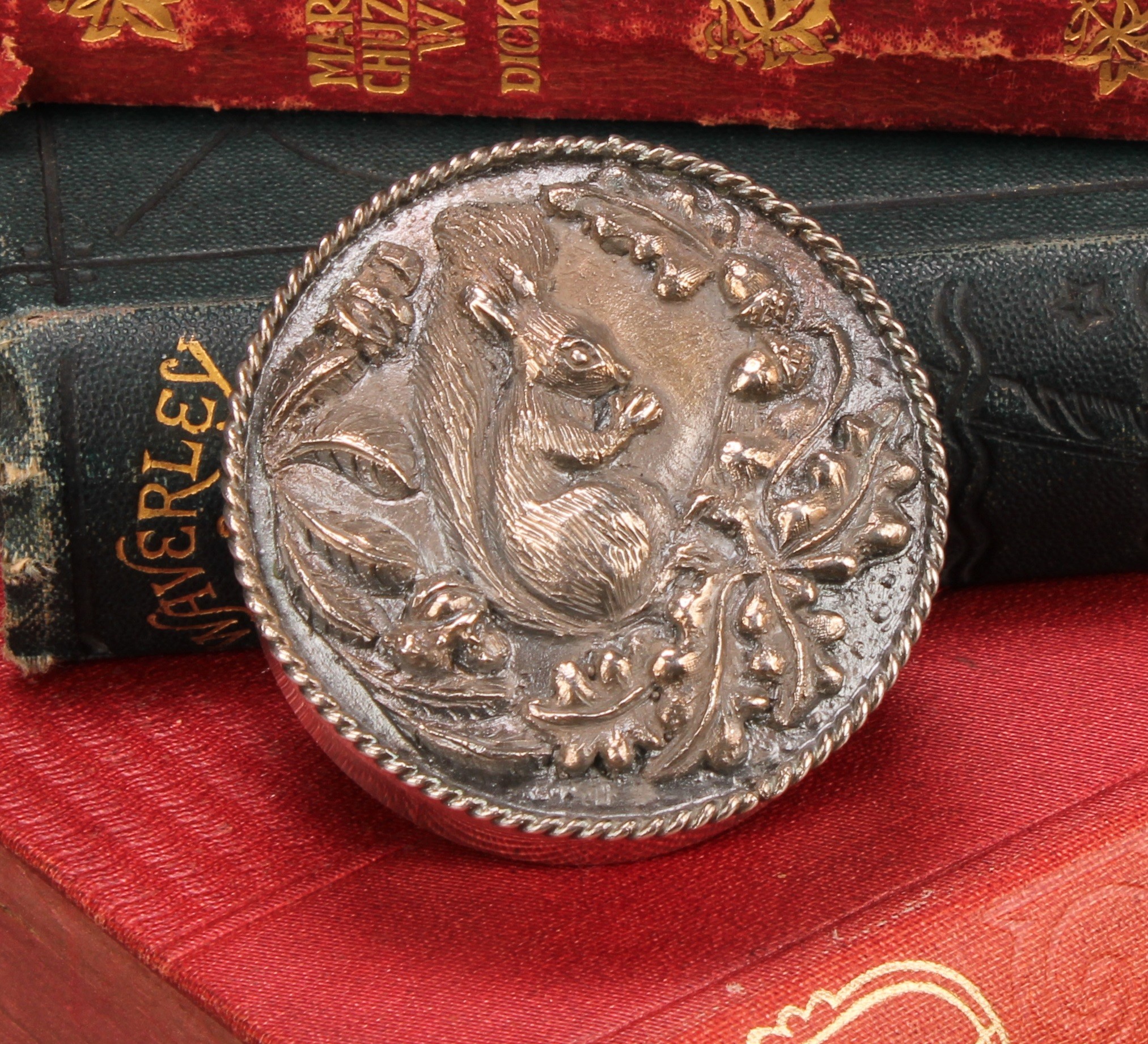 An Elizabeth II silver circular trinket box, the push-fitting cover in relief with a squirrel,