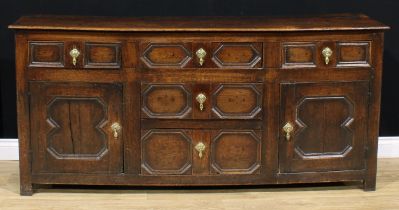 A late 17th century oak low dresser, oversailing top above an arrangement of drawers and panel