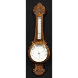 An early 20th century oak wheel barometer, 18.5cm circular register, the case carved with an
