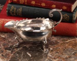 A George II silver sauce boat, acanthus-capped flying scroll handle, wavy border, hoof feet,