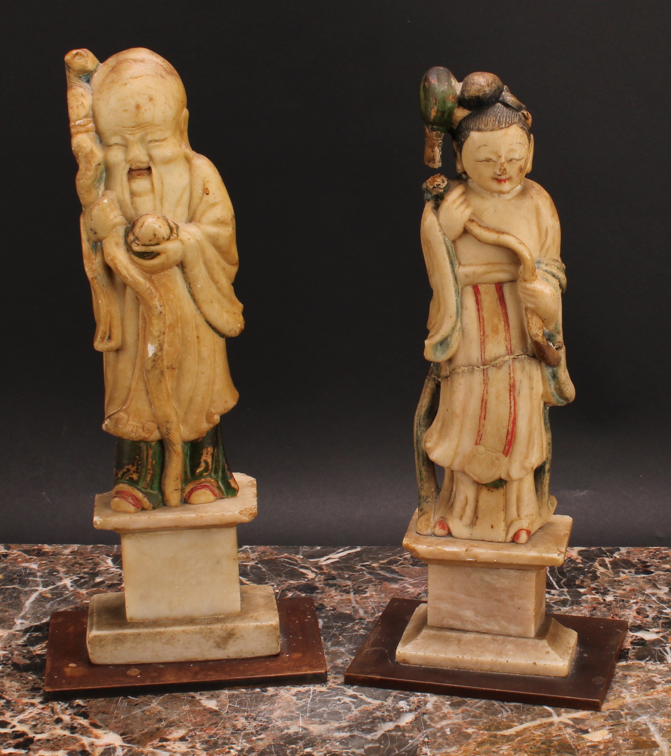 A pair of Chinese soapstone figures, carved as Shou Lao and Guanyin, each picked out in