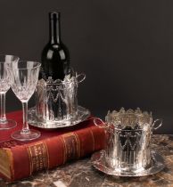 A pair of Edwardian silver syphon stands or bottle coasters, pierced and embossed in the Neo-