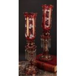 A pair of Bohemian cranberry flashed glass storm lantern candle lustres, decorated in opaque