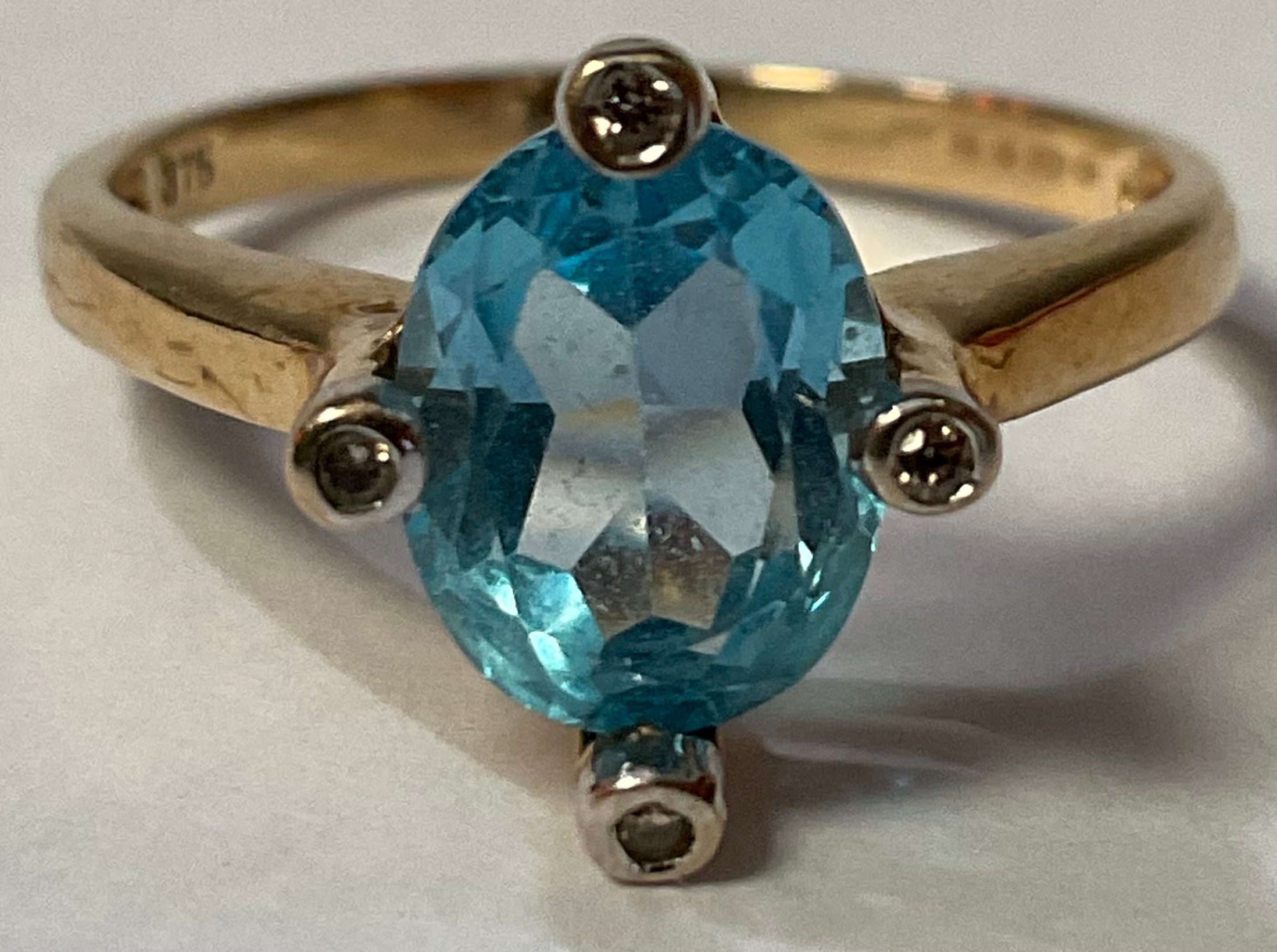 A 9ct gold ring, set with a central faceted topaz, surrounded by four illusion set diamond chips,
