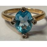 A 9ct gold ring, set with a central faceted topaz, surrounded by four illusion set diamond chips,