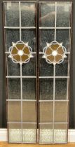 A pair of tall stained glass window panels, each with a red, white and blue rose motif, approx.