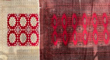 A Middle Eastern woolen rug or carpet, worked with geometric motifs, in tones of red and black,