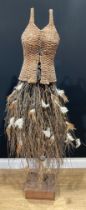 A rustic wicker display mannequin, wicker bodice, hazel twig and feather skirt, on wooden stand,