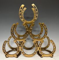 A contemporary brass coloured metal six bottle wine rack, horseshoe design, 40cm high, 41cm wide