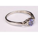 A tanzanite and white sapphire ring, the central blue oval facet cut stone flanked by 8 small