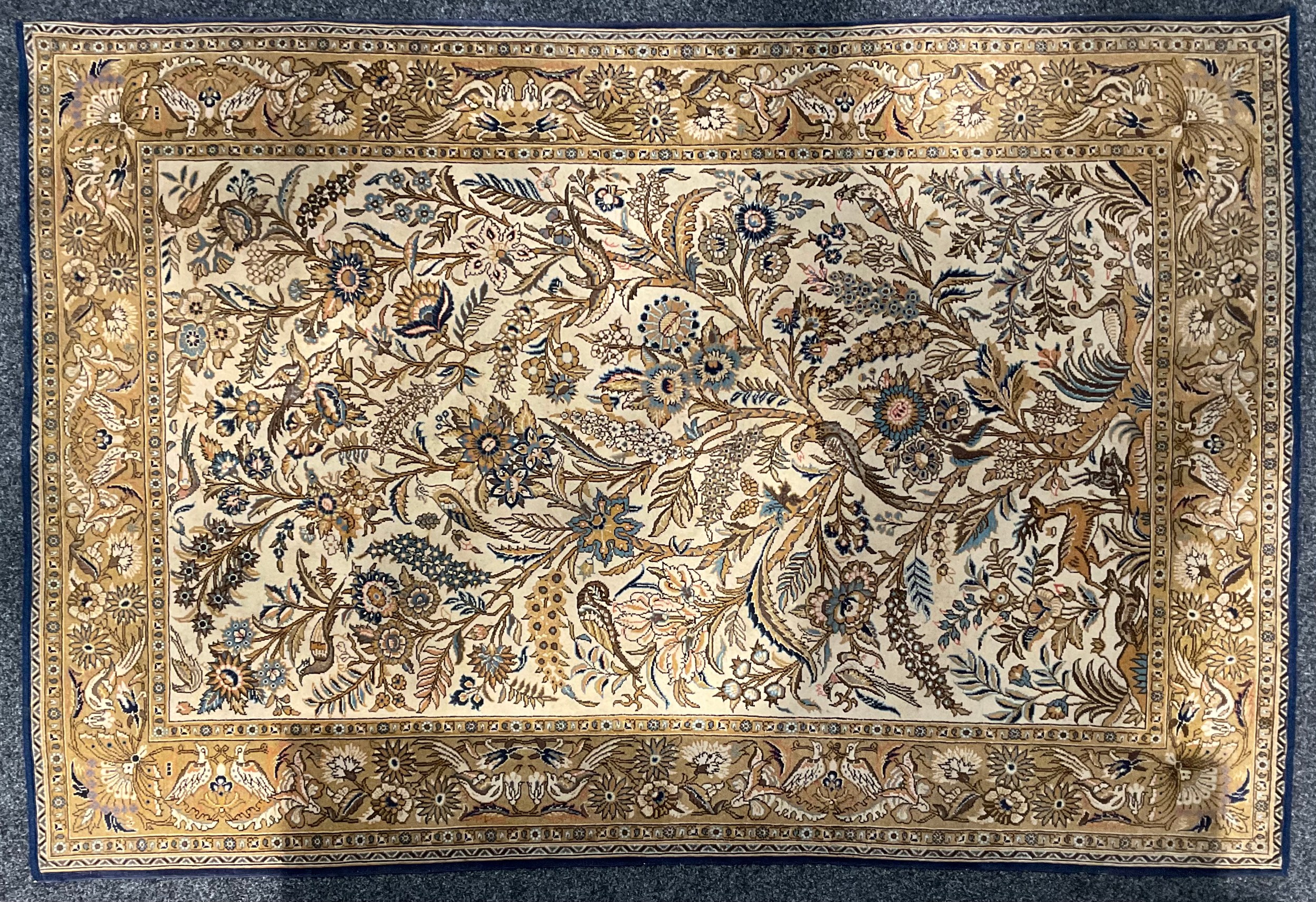 An Iranian silk Gohm type rug, decorated with birds and flowering foliage, in shades of golden