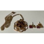 A 9ct gold openwork shaped circular pendant set with an arrangement of garnets, marked 375,