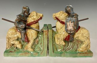 A pair of terracotta bookends as medieval jousting knights on horseback, gloss glazed in shades of