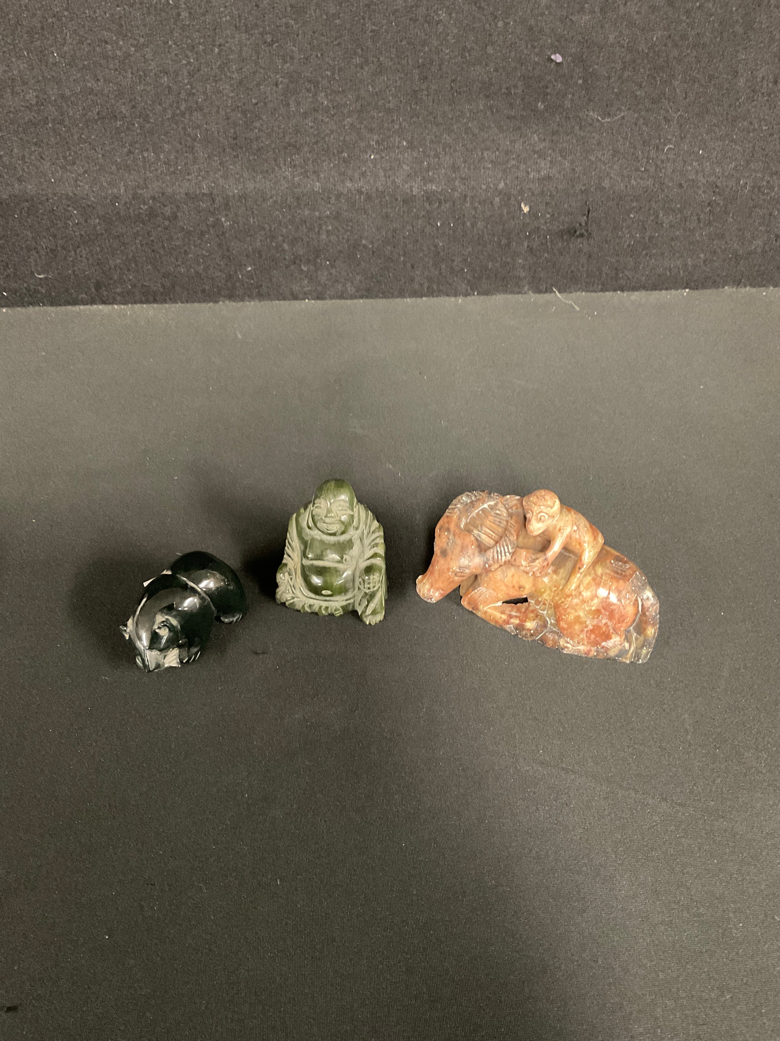 A Chinese hardstone buddha; a soapstone bear with fish; a soapstone monkey on oxen